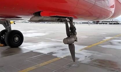 A red aircraft with a ram air turbine at the bottom